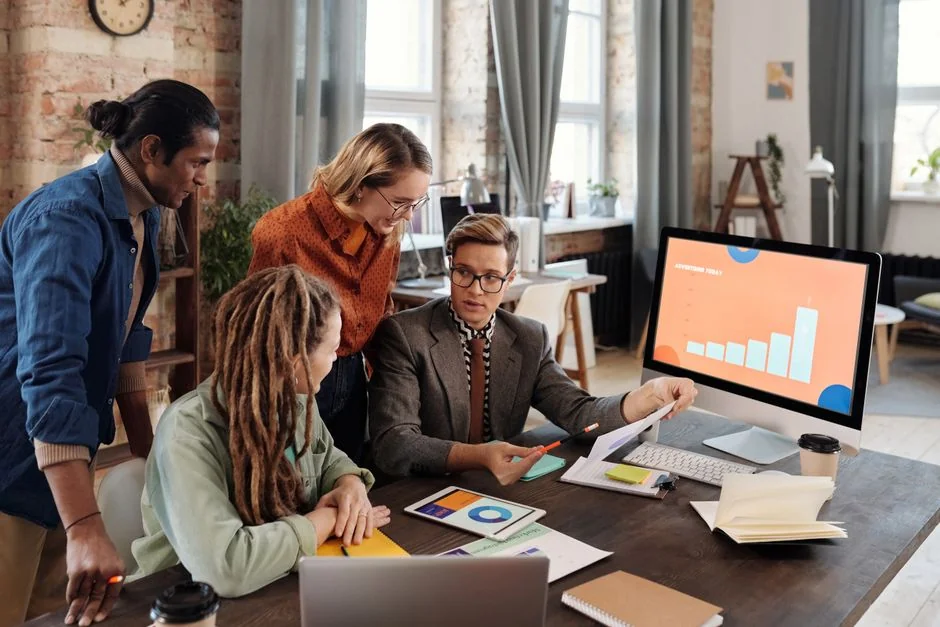 A diverse team collaborating on digital marketing strategies at a desk, using laptops and tablets.
